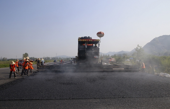 2019年8月，宜春經(jīng)開區(qū)S311路面攤鋪現(xiàn)場，工友們輔助路面兩側(cè)的分料、補窩等作業(yè)